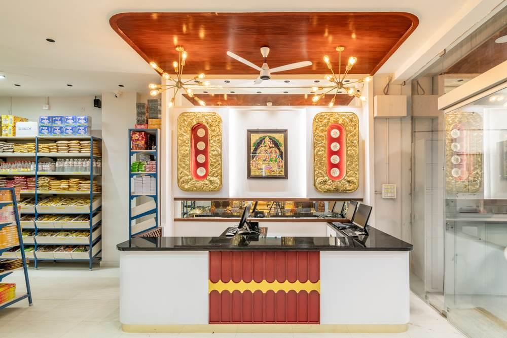 Checkout counter with traditional red and gold panelling in a pooja and home store by Arch Decode